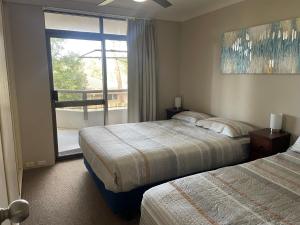 a hotel room with two beds and a window at The Commodore, 14, 9-11 Donald Street- Unit in the heart of town with views & free wi-fi in Nelson Bay