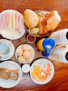 uma mesa com pratos de diferentes tipos de alimentos em Chalés Raios de Sol em Monte Verde