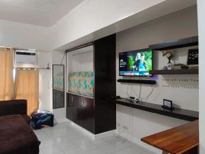 a living room with a couch and a tv on a wall at B123 Unit 1852 Prime Residences Tagaytay in Tagaytay