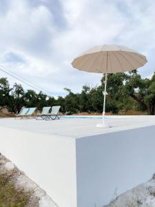 a table with an umbrella and chairs and a pool at Monte da Borrega - Casa de Campo in Esperança