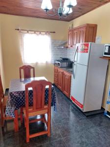 uma cozinha com um frigorífico branco e uma mesa com cadeiras em Hotel y Departamentos Arroyos em Perico