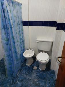 a bathroom with a toilet and a shower curtain at Hotel y Departamentos Arroyos in Perico