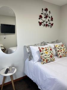 a bedroom with a white bed with a mirror and a table at Alto da Villa Loft in Ouro Preto