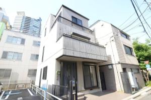 a tall white building with a balcony on a street at la3 hotel annex 新宿三階建て一軒家 in Tokyo