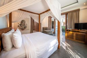 a bedroom with a white bed with a television at Villa Alopa Seminyak in Seminyak