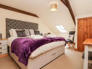 a bedroom with a large bed with a purple blanket at Wheal Prosper in St Austell