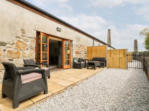 a patio with wicker chairs and tables and a building at Wheal Prosper in St Austell