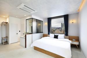 een slaapkamer met een groot wit bed en een raam bij Hotel Intro Chuncheon in Chuncheon