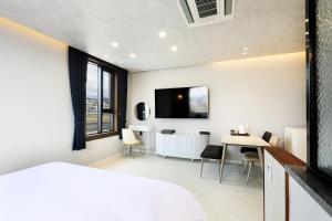 Hotel Intro Chuncheon في تشنتشون: غرفة نوم بسرير وطاولة مع كراسي