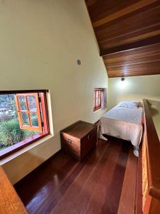 um quarto com uma cama e uma janela em Chalés Bela Vista em Monte Verde