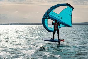 un hombre de pie en una tabla de surf con una vela grande en Sleep Space - Green Tiny Spot Steinhuder Meer en Neustadt am Rübenberge