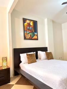 uma cama num quarto com um quadro na parede em Aparta Hotel Roma em Santo Domingo