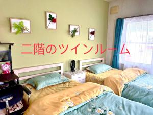 twee bedden in een kamer met schrijfwerk aan de muur bij PENSION YunShuiYao雲水瑶民宿 in Furano