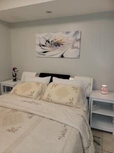 uma cama com lençóis brancos e uma pintura na parede em RoryHouse em Toronto