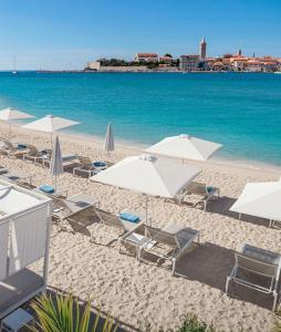 a beach with white umbrellas and chairs and the ocean at Holiday house with a parking space Mundanije, Rab - 18889 in Rab