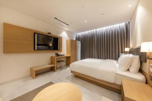 a hotel room with a bed and a television at Masan Daisy Hotel in Changwon