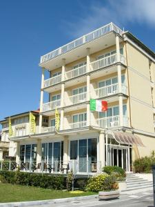 un bâtiment avec drapeaux devant lui dans l'établissement Savoy Hotel, à Marina di Pietrasanta