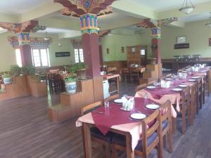 a dining room with long tables with red tablecloths at Hotel Kang Lha Chen in Leh