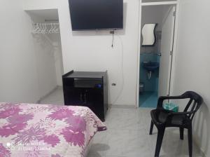 1 dormitorio con 1 cama, 1 silla y TV en Angello, en Lima
