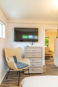 Zimmer mit einem Stuhl und einer Kommode mit einem TV in der Unterkunft Delightful Cottage in Seaside Town of La Jolla Village in San Diego