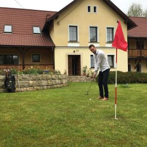 Un uomo che gioca a golf in un giardino con bandiera rossa di Hajduk Apartment a Międzylesie