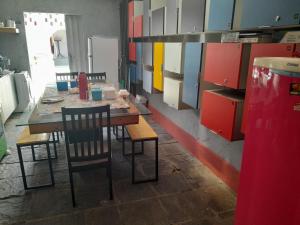 una cucina con tavolo, sedie e armadi di "LE CHAT QUI PECHE" Hostel a 150 metros da PRAIA de PAJUCARA a Maceió