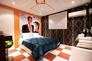 ein Schlafzimmer mit einem Poster von einem Mann und einer Frau in der Unterkunft Jeonju Blue One in Jeonju