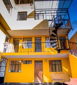 ein gelbes Haus mit einem Balkon und einem Stuhl in der Unterkunft CAYESH Guest House in Huaraz