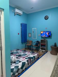 a blue room with a bed and a tv at Bu Sur Homestay in Bogor