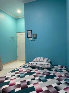 a bedroom with a bed with a blue wall at Bu Sur Homestay in Bogor