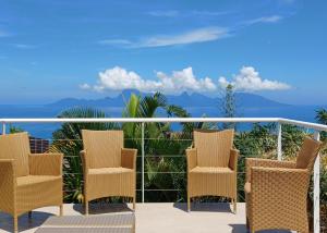 a balcony with chairs and a view of the ocean at Logement Cosy avec Piscine et Vue Tahiti Punaauia in Punaauia