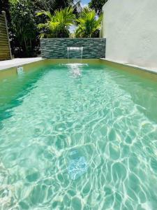 una piscina de agua azul clara con una silla. en Villa Exotic Life récente avec piscine, 2 chambres, 2 SDB, en Le Moule