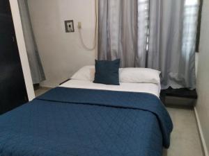 a bedroom with a blue and white bed with a blue blanket at Departamentos de la Reina Roja in Palenque