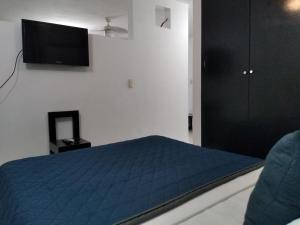 a bedroom with a blue bed and a flat screen tv at Departamentos de la Reina Roja in Palenque