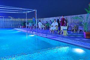 un grupo de personas sentadas alrededor de una piscina por la noche en Regenta Orkos Kolkata by Royal Orchid Hotels Limited en Calcuta