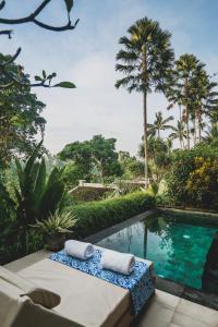 a swimming pool with two towels sitting on a table at Amora Ubud Boutique Villas in Ubud
