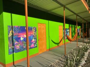 a green building with hammocks and paintings on it at Yejos in Dos Brazos