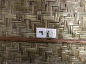 two electrical outlets on a wall with a stone wall at Joben Ecolodge in Tetebatu