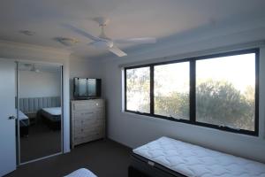 een slaapkamer met een bed, een raam en een televisie bij Moreton Magnificent Views in Tangalooma