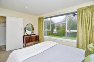 a bedroom with a bed and a large window at Charlesworth Villa - Christchurch Holiday Homes in Christchurch