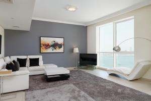 a living room with a white couch and a tv at Maison Privee - Jaw-Dropping Sea Vw in Luxury Apt with Delux Fittings in Dubai