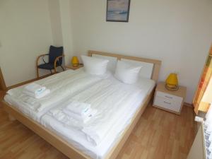 a bedroom with a bed with white sheets and pillows at Sonnige-Ferienwohnung-100qm-im-1-Obergeschoss-der-Villa-Walhall-in-einem-parkaehnlichen-Garten in Ostseebad Sellin