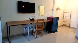 a desk with a chair and a television on a wall at The Sekret Hotel in Sungai Kolok