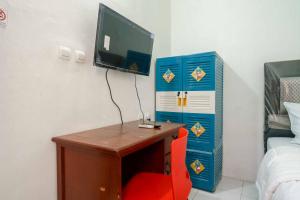 a room with a desk with a tv and a red chair at KoolKost Syariah @ Citraland Puri Serang in Serang