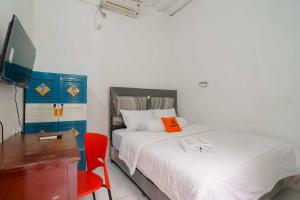 1 dormitorio con cama, escritorio y silla roja en KoolKost Syariah @ Citraland Puri Serang, en Serang