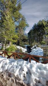 a wooden bridge covered in snow next to a fence at La Ruta de Los Volcanes - Las Trancas Chillán in Las Trancas