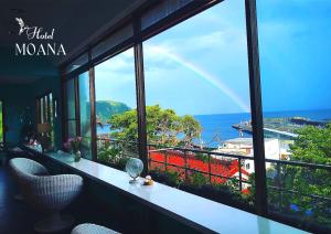 uma vista para o oceano a partir de uma varanda com um arco-íris em Hotel MOANA絶景オーシャンビューカフェラウンジ em Oshima