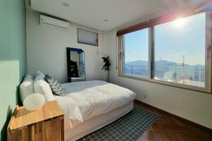 - une chambre avec un lit et une grande fenêtre dans l'établissement Naksan Balcony, à Séoul