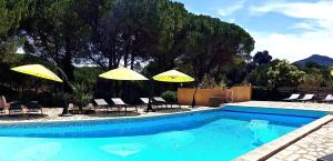 - une piscine avec 2 parasols et chaises jaunes dans l'établissement Auberge Val Moureze Hôtel & Spa, à Mourèze