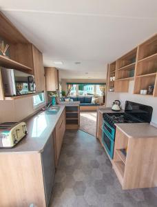 a kitchen with wooden cabinets and a stove top oven at Spacious Caravan - Thorpe Park Cleethorpes in Humberston